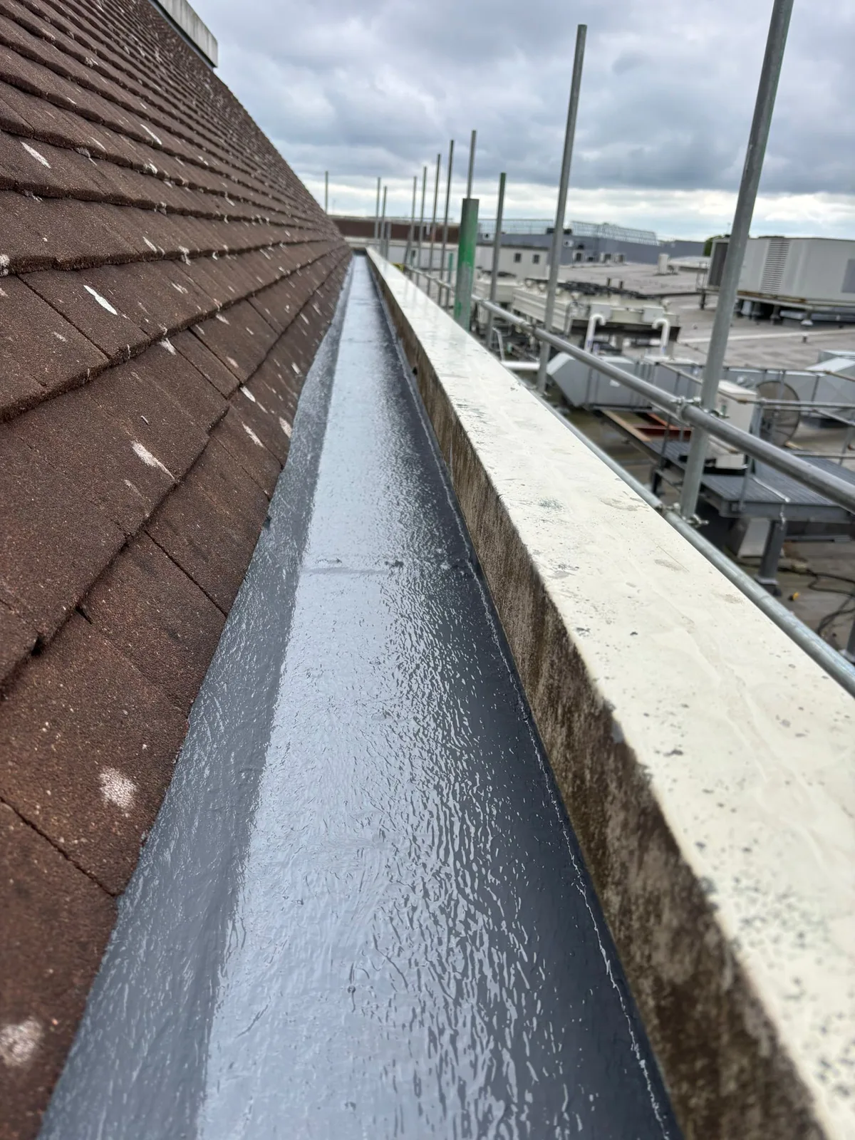 Low view along the lined gutter channel beside the roof edge