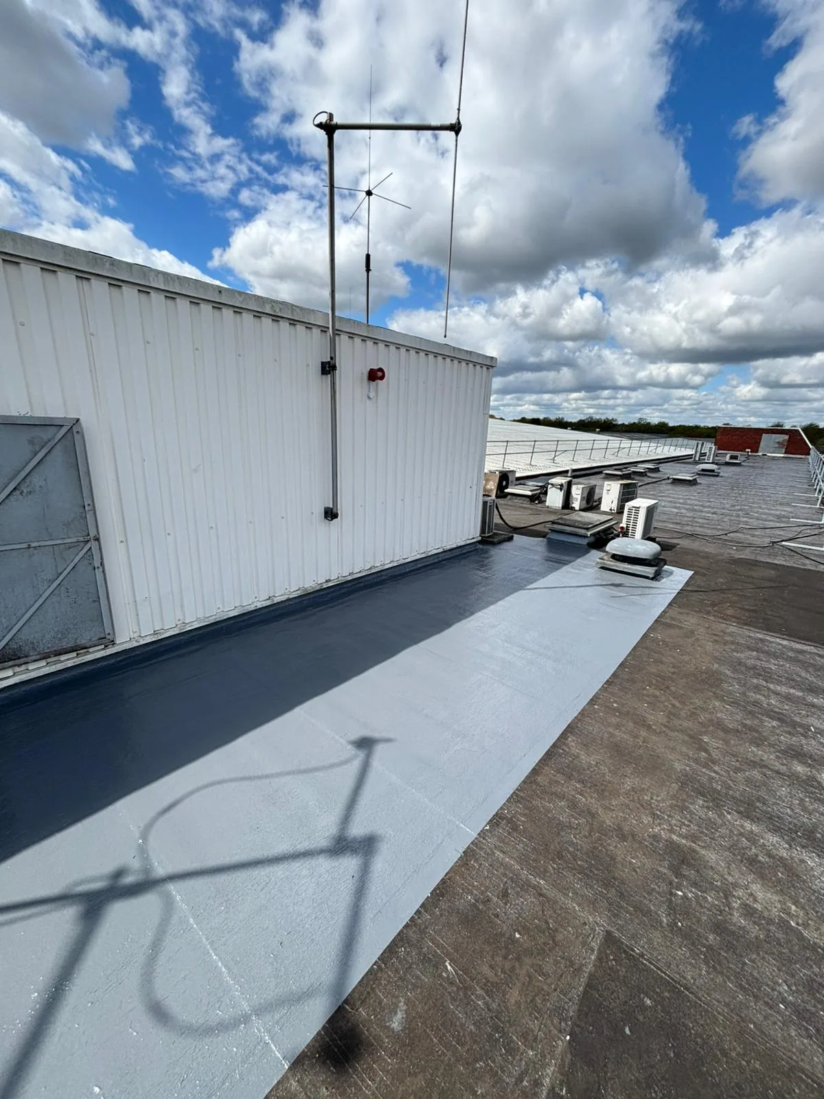 Liquid waterproofing patch beside a rooftop plant enclosure in Hemel Hempstead